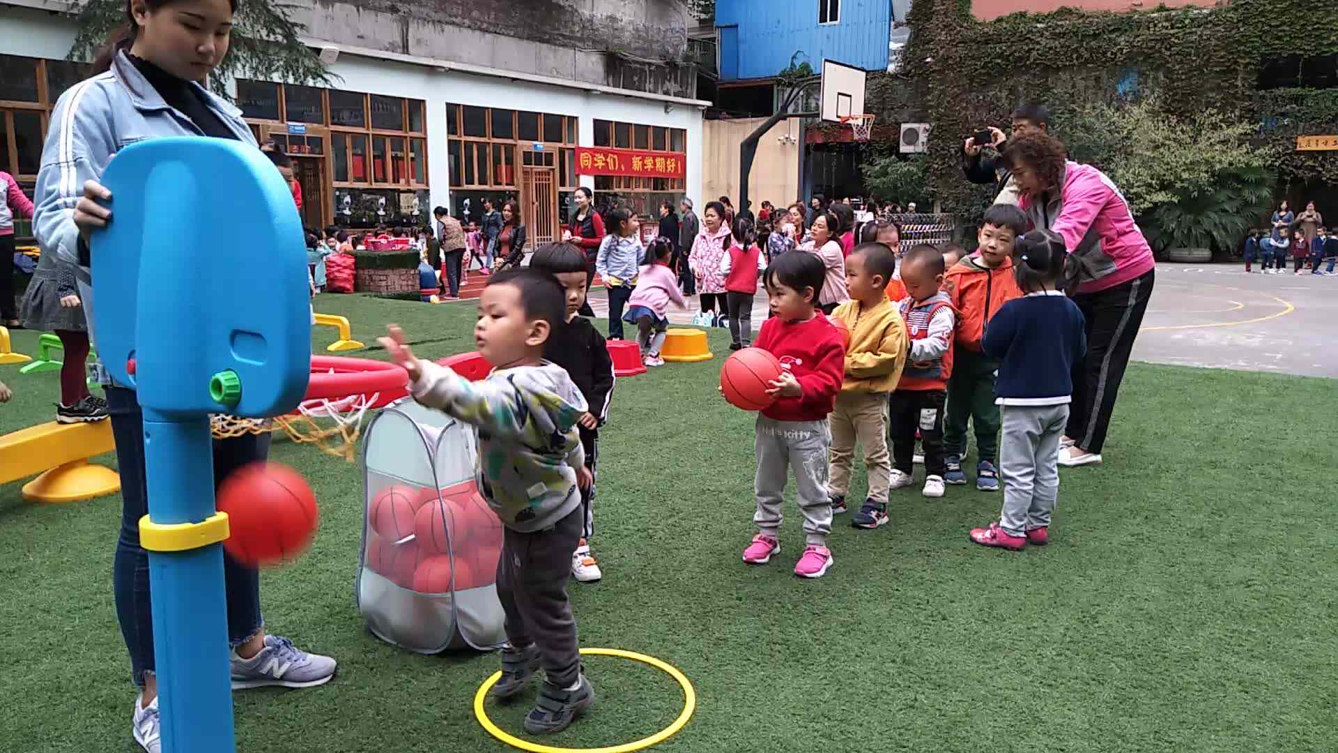 萌娃们在老师的帮助下投球